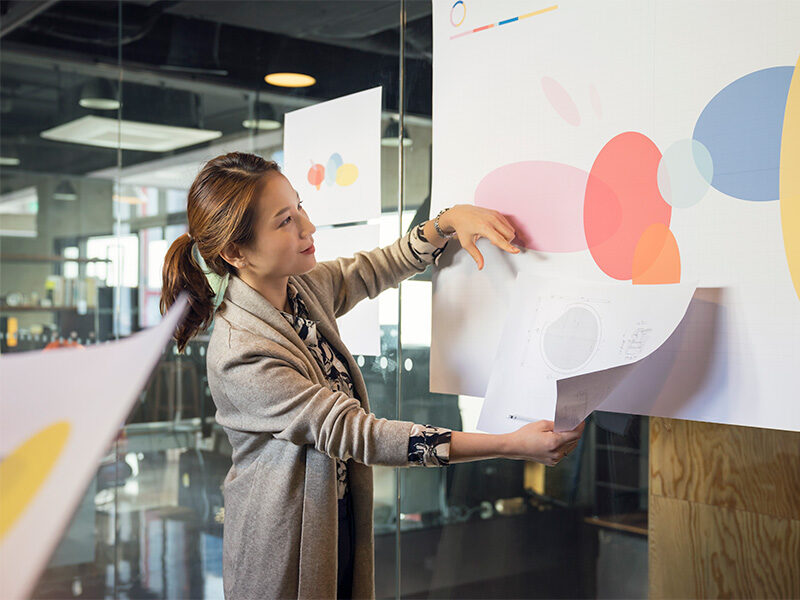 Asian woman comparing charts on whiteboard