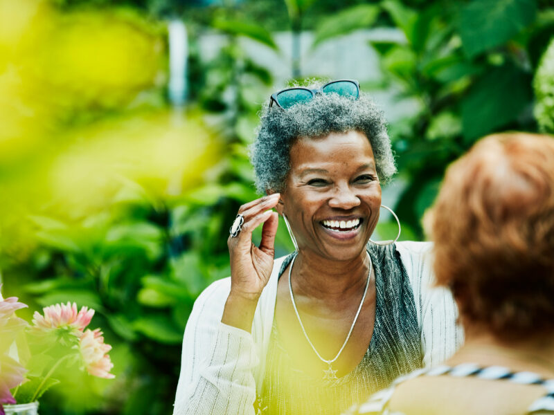 Laughing woman hanging out with friends during backyard dinner party.