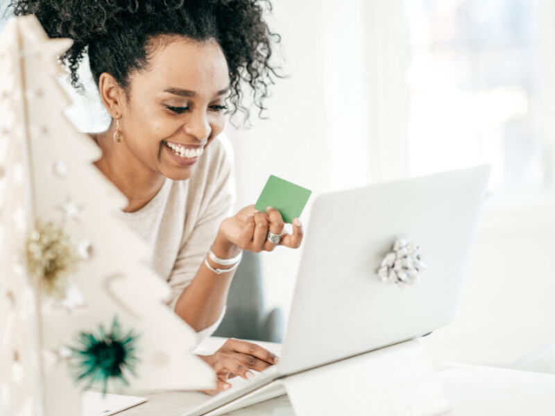 Smiling young woman managing online banking on laptop, working on her finances while relaxing at home.