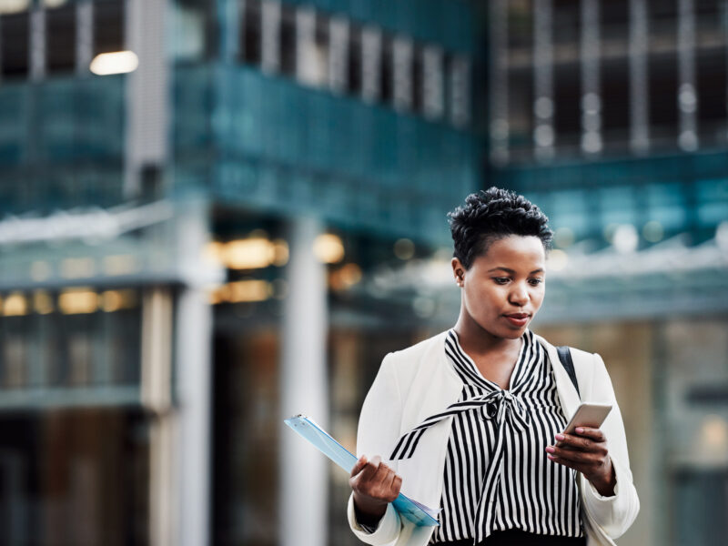 Female professional leaving office looking at phone.