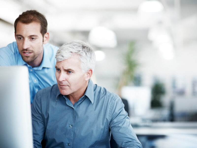 photo of two office employees looking at the computer screen