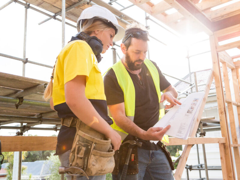 male and female construction workers discuss the building plans inside the building site