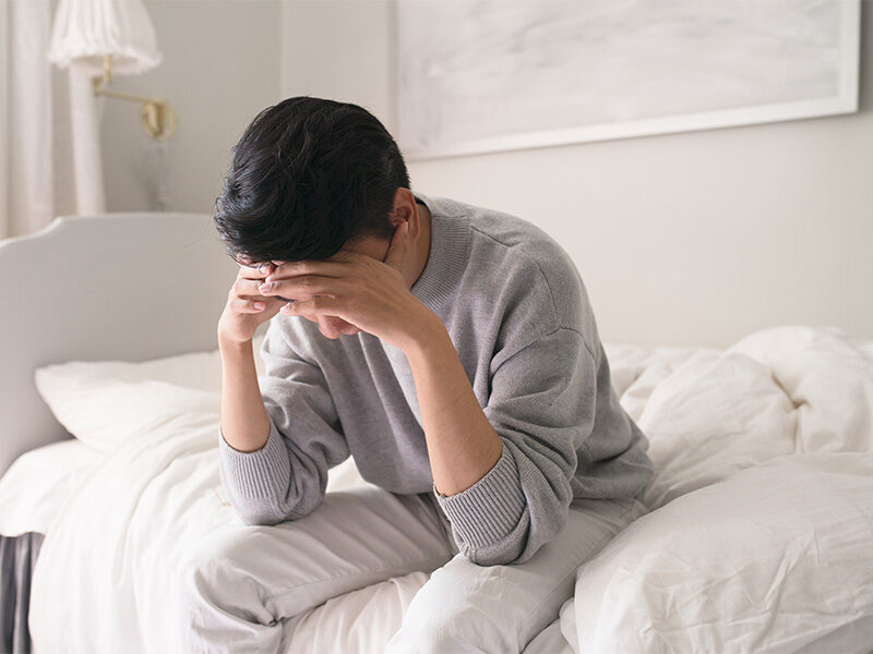 Woman seated on her bed worrying