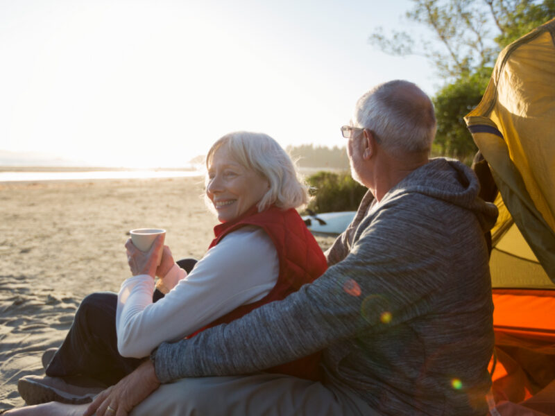 Senior couple sitting on beach camping enjoying the sunshine.