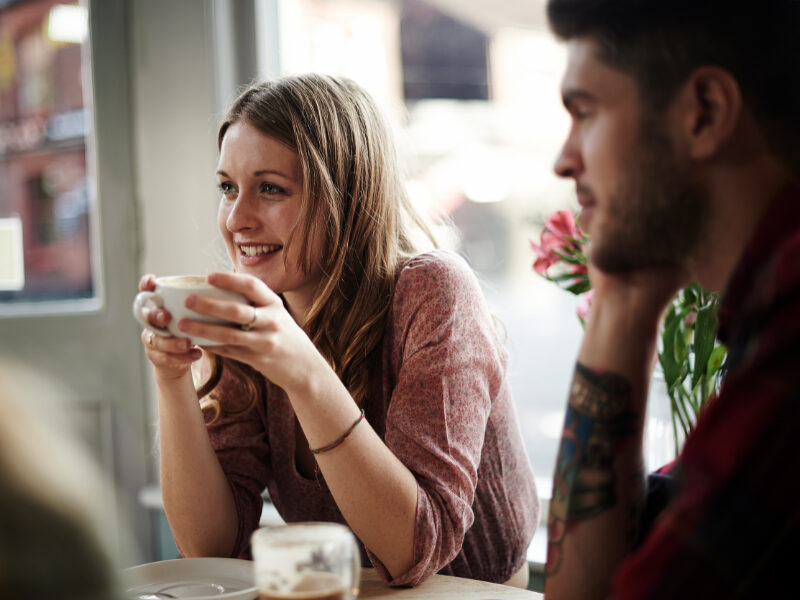 Woman enjoying hot beverage speaking with a group.