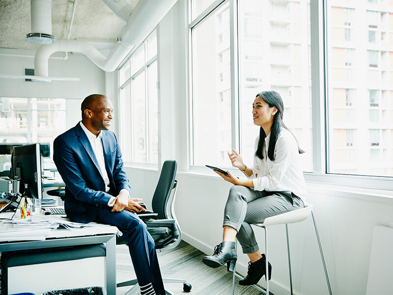 Two working professionals conversing in the office.