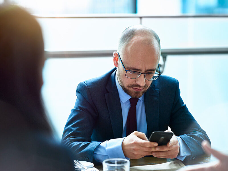 Business professional male looking at phone.