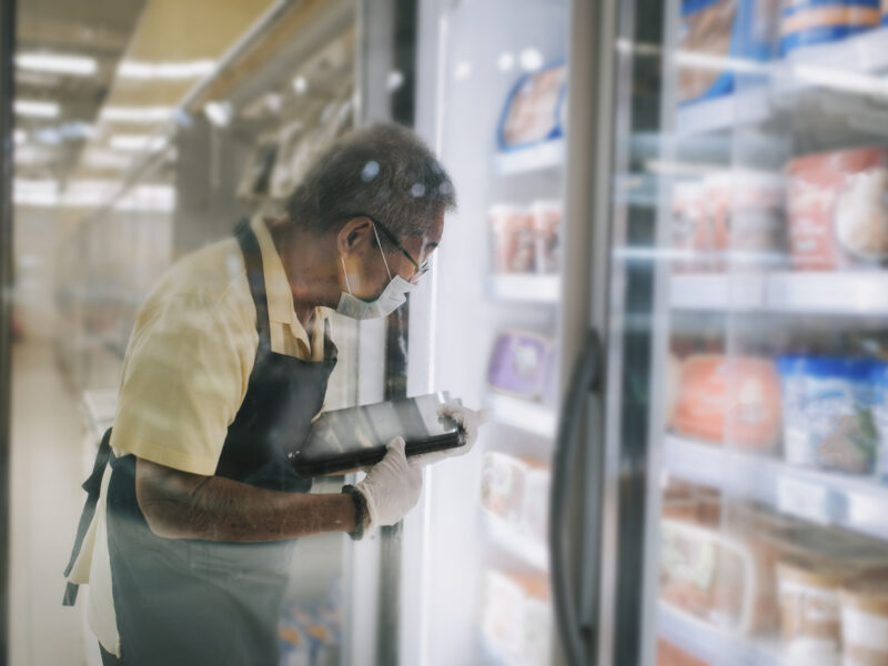 An Asian Chinese senior man supermarket shopkeeper retail assistant with face mask