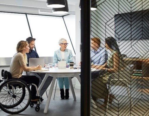 Male and female professionals discussing in board room. Disabled businesswoman communicating with coworkers in meeting. They are at office.