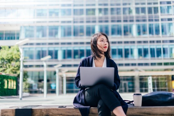 Professional woman with laptop outside.