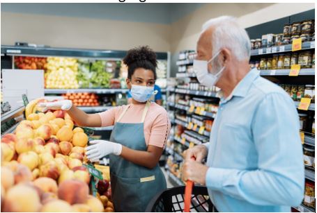 Senior male at the grocery store happily speaking to store employee.