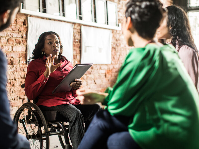 Businesswoman in wheelchair leading group discussion in creative office