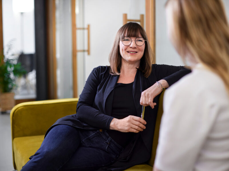 Two businesswomen talking on couch in office